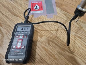 Using a Tramex hammer pin meter to measure moisture content in flooring after a failure, helping identify the source of the problem.